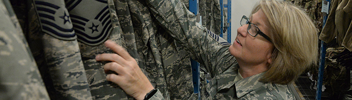 A service member sorts a rack of uniforms